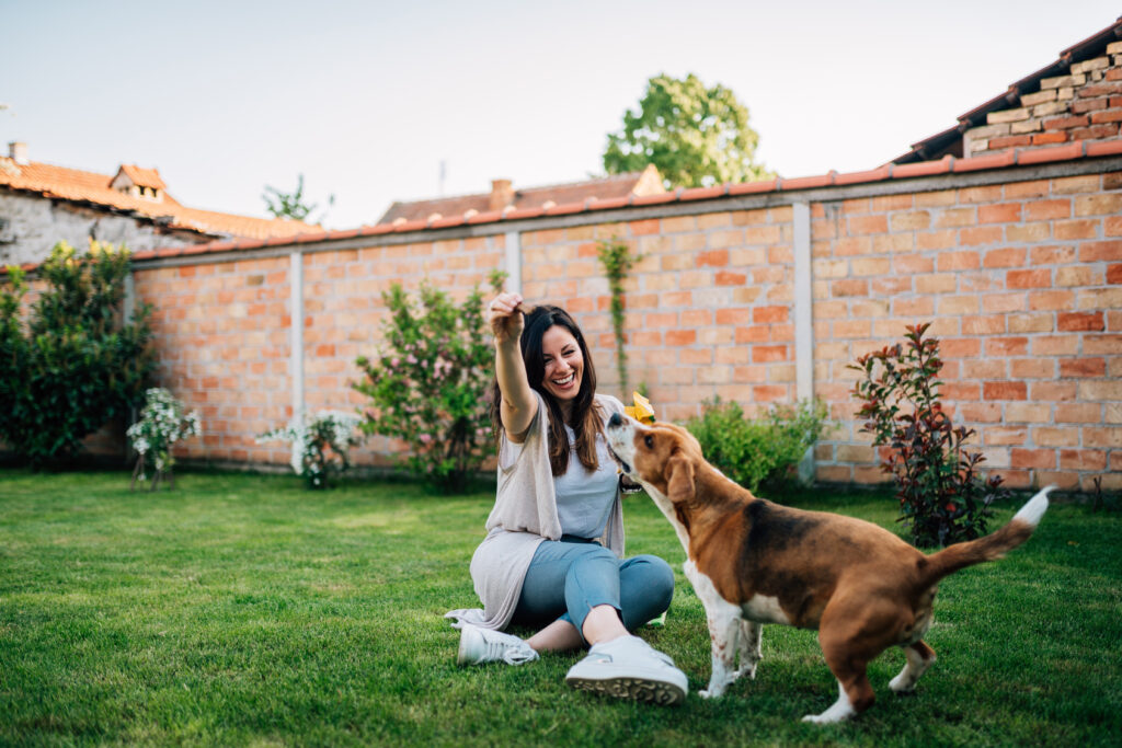 Une jeune femme joue avec son chien dans le jardin.