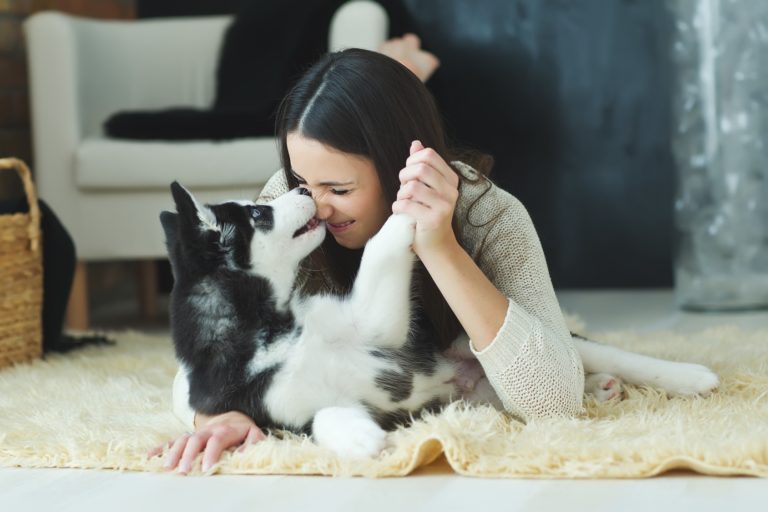 Frau-kuschelt-mit-Husky-Hund-auf-Teppich-768×512